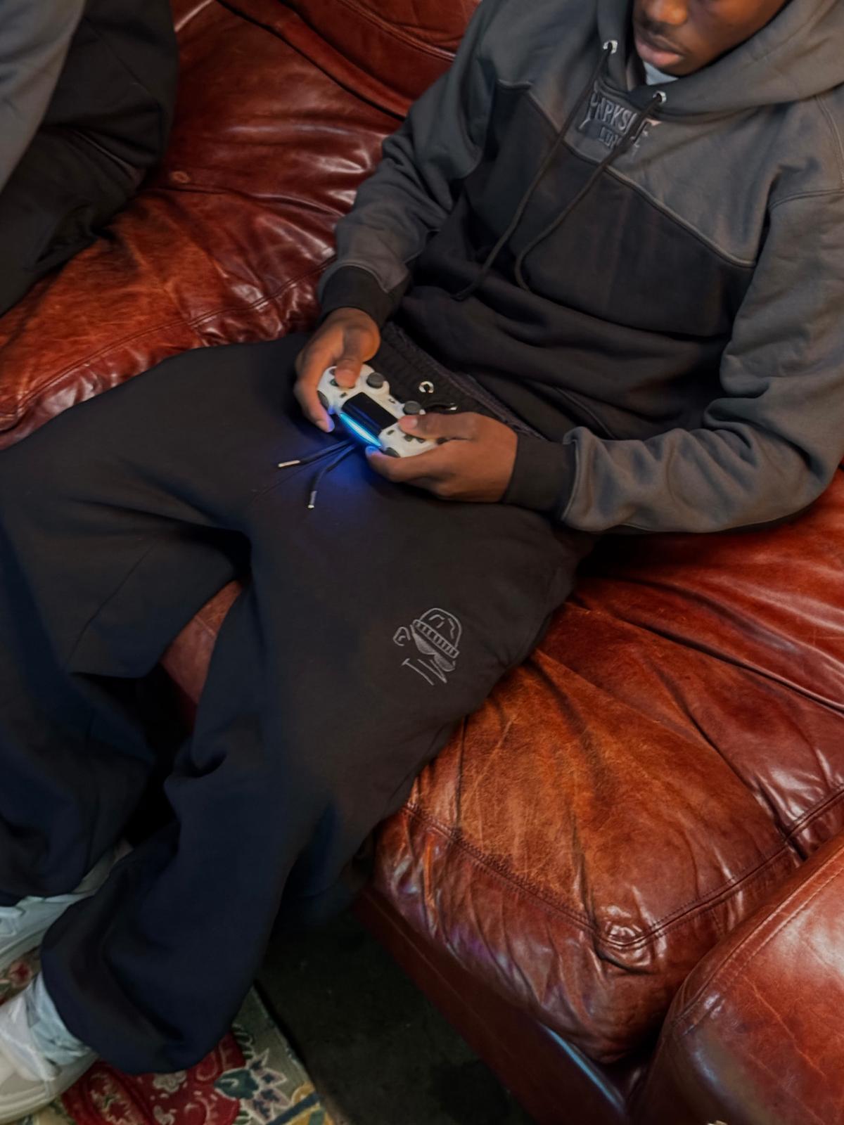 Parkside black joggers — seated front view and embroidered thigh detail